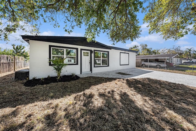 view of front of house with stucco siding, a patio area, central AC, and fence