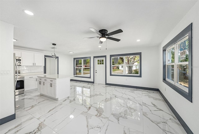 interior space with plenty of natural light, baseboards, marble finish floor, and ceiling fan