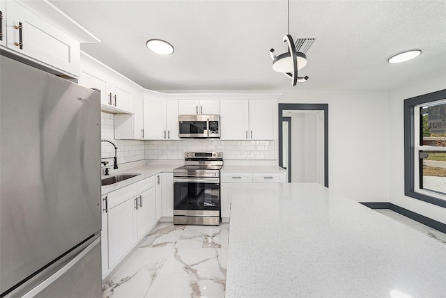 kitchen featuring decorative backsplash, marble finish floor, appliances with stainless steel finishes, and a sink