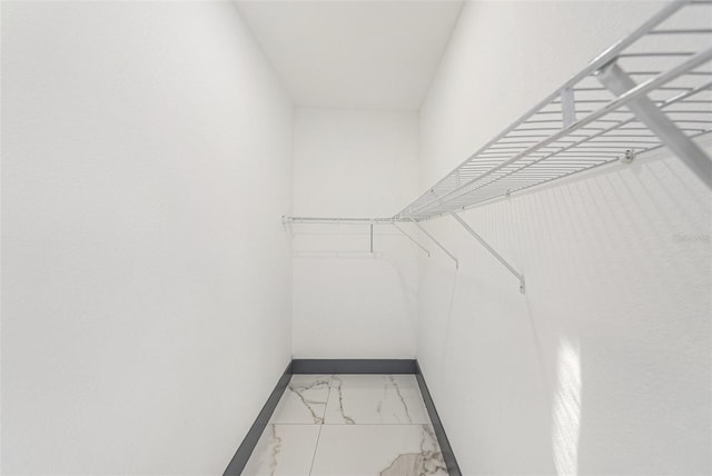 walk in closet featuring marble finish floor