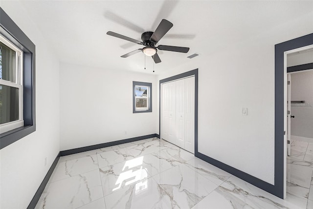 unfurnished bedroom featuring visible vents, marble finish floor, a ceiling fan, a closet, and baseboards