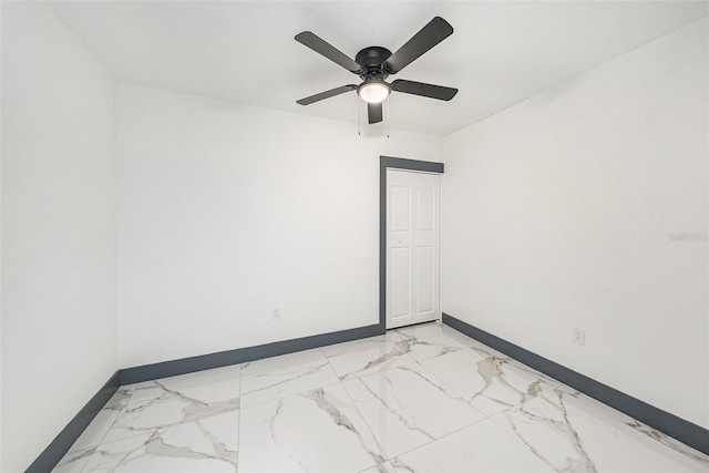 empty room featuring baseboards, marble finish floor, and ceiling fan