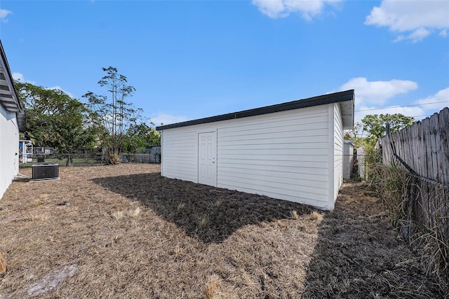 view of outdoor structure with an outbuilding, central AC unit, and fence private yard