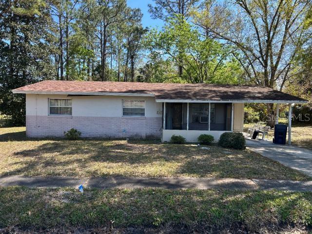 ranch-style home with brick siding, an attached carport, driveway, and a front yard