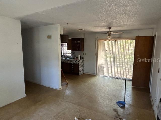 interior space with a textured ceiling, concrete flooring, and ceiling fan