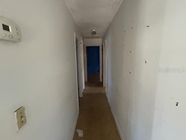 hallway with baseboards and a textured ceiling