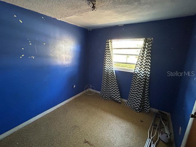 empty room with carpet, baseboards, and a textured ceiling