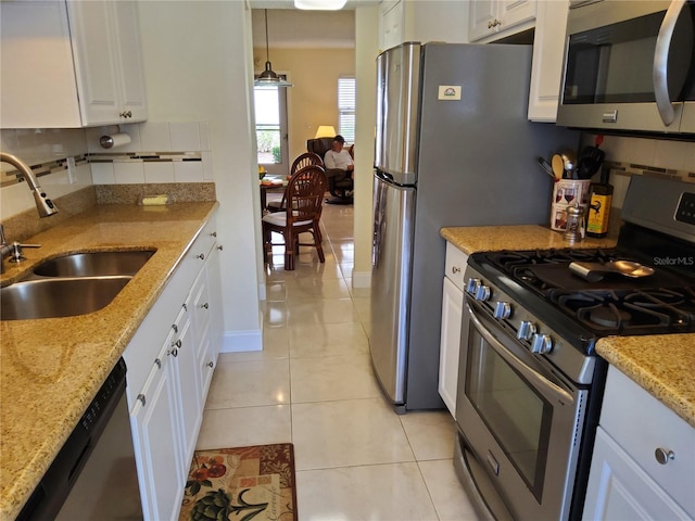 kitchen with light tile patterned floors, decorative backsplash, appliances with stainless steel finishes, white cabinets, and a sink