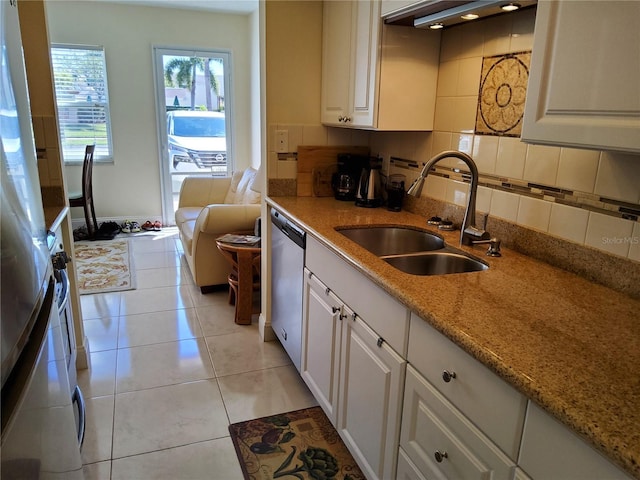 kitchen with light tile patterned flooring, backsplash, dishwasher, and a sink