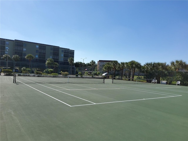 view of tennis court with community basketball court and fence