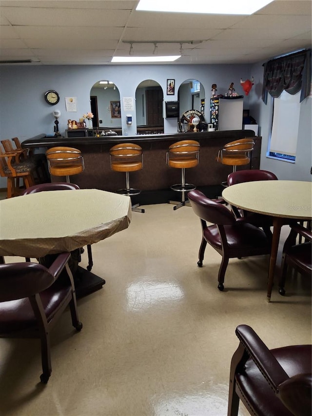 interior space featuring tile patterned floors, a community bar, a drop ceiling, and track lighting