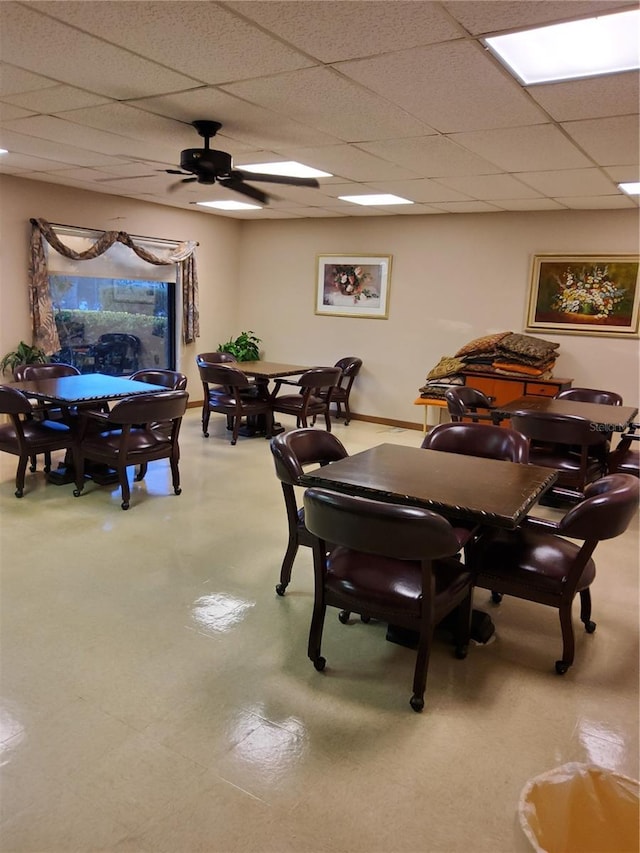 dining room featuring a drop ceiling, light floors, and a ceiling fan