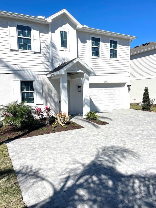 view of front facade featuring an attached garage, driveway, and stucco siding