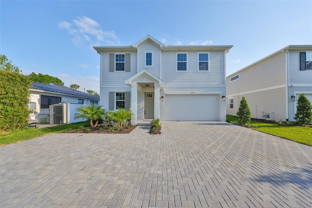 view of front of house with an attached garage, decorative driveway, and fence