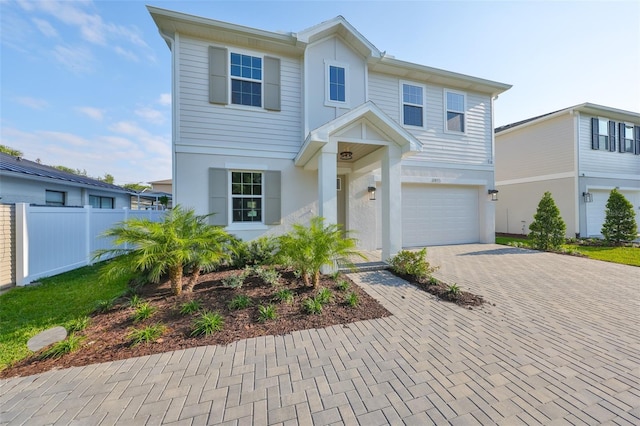 view of front facade with stucco siding, an attached garage, fence, and decorative driveway