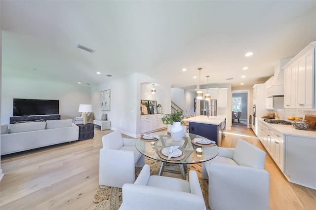 living room featuring light wood-style flooring, baseboards, visible vents, recessed lighting, and stairway