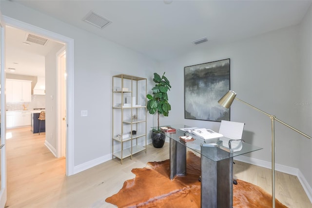 home office with baseboards, visible vents, and light wood-type flooring