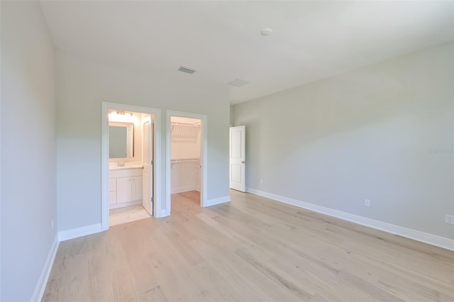 unfurnished bedroom featuring light wood-type flooring, baseboards, visible vents, a spacious closet, and a closet