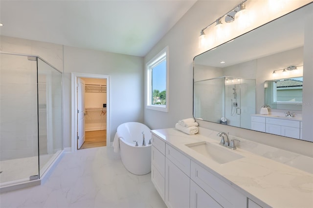 full bathroom with a shower stall, marble finish floor, vanity, a walk in closet, and a freestanding tub