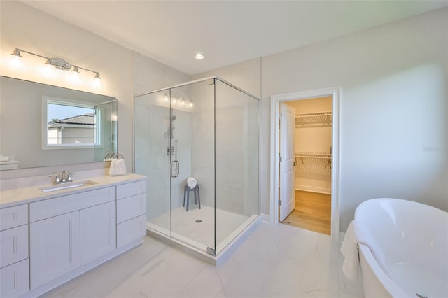bathroom featuring a shower stall, a spacious closet, vanity, marble finish floor, and a soaking tub