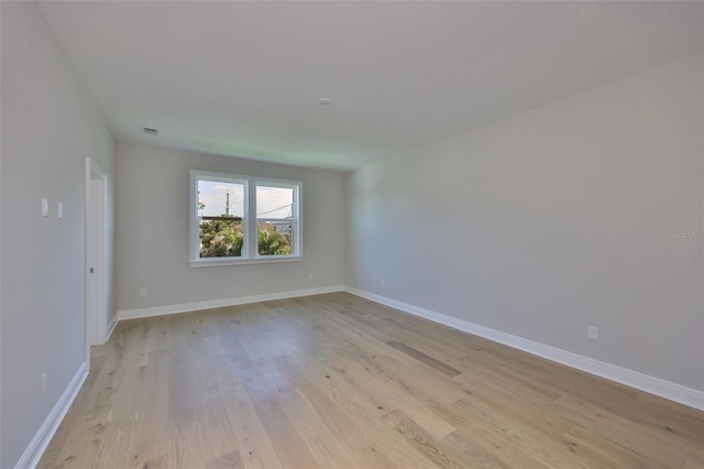 unfurnished room featuring baseboards, visible vents, and light wood finished floors