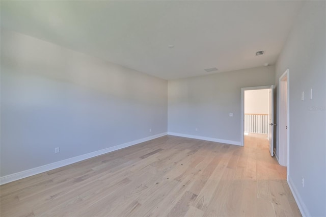 spare room with light wood finished floors, baseboards, and visible vents