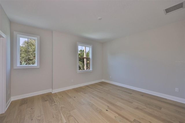 spare room with light wood-style flooring, visible vents, and baseboards
