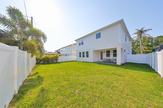 rear view of property featuring a lawn, a fenced backyard, and a patio area