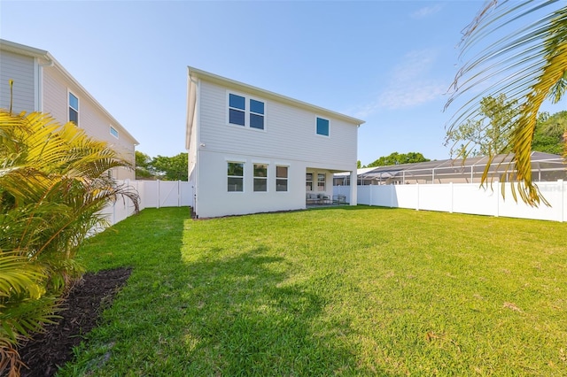 rear view of house featuring a yard and a fenced backyard
