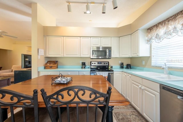 kitchen with light countertops, stainless steel appliances, white cabinets, a textured ceiling, and a sink