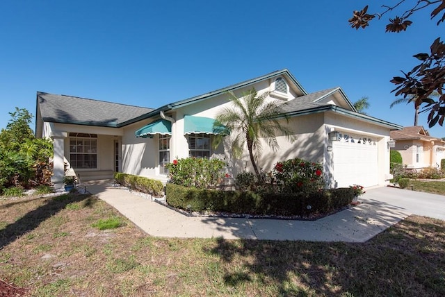 view of front of home with concrete driveway, an attached garage, a front yard, and stucco siding