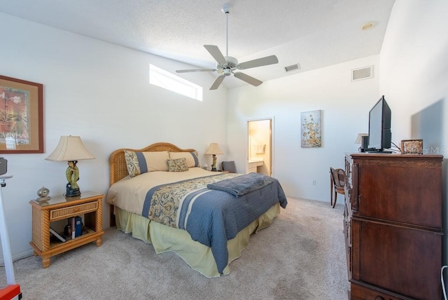 carpeted bedroom featuring visible vents, a textured ceiling, ensuite bathroom, and a ceiling fan