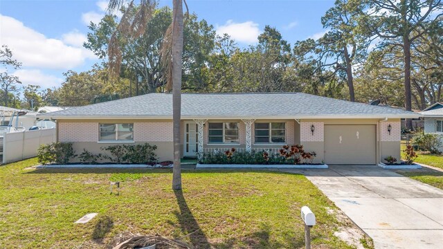 single story home featuring driveway, a front lawn, fence, a garage, and brick siding