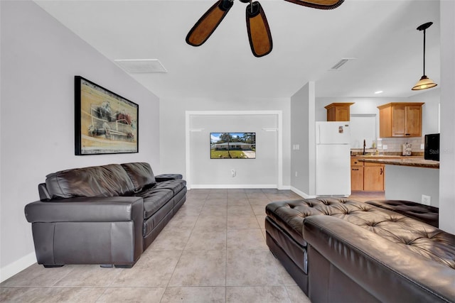living room with light tile patterned floors, visible vents, baseboards, and a ceiling fan