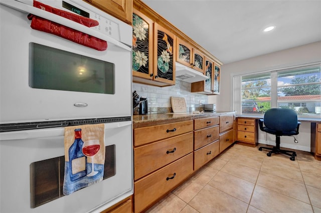 kitchen featuring backsplash, recessed lighting, double oven, light tile patterned floors, and glass insert cabinets
