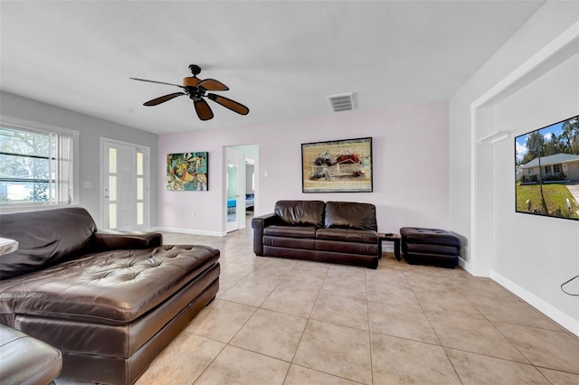 living area featuring light tile patterned floors, visible vents, baseboards, and a ceiling fan