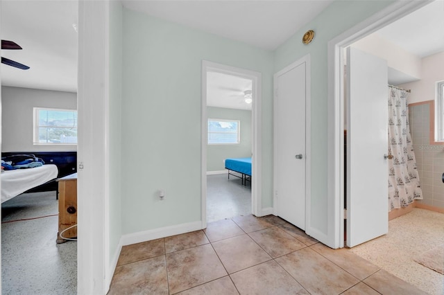 hallway featuring a wealth of natural light, baseboards, and light tile patterned flooring