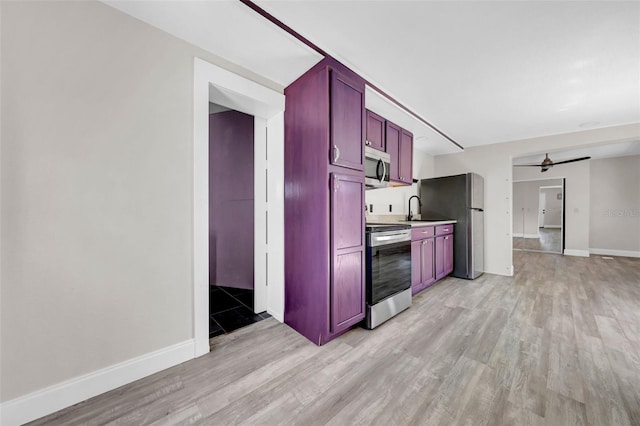 kitchen with reddish brown cabinets, ceiling fan, light wood-type flooring, stainless steel appliances, and a sink