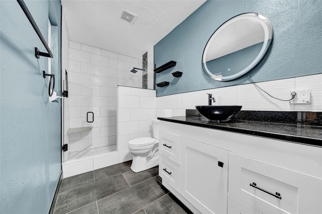full bath featuring visible vents, a shower stall, toilet, vanity, and tile walls