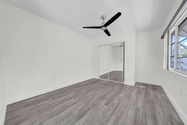unfurnished bedroom with a ceiling fan, wood finished floors, baseboards, and a closet