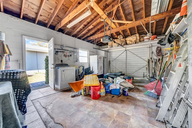 garage with a garage door opener, freestanding refrigerator, and washing machine and clothes dryer
