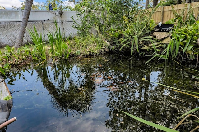 view of water feature with a small pond and fence