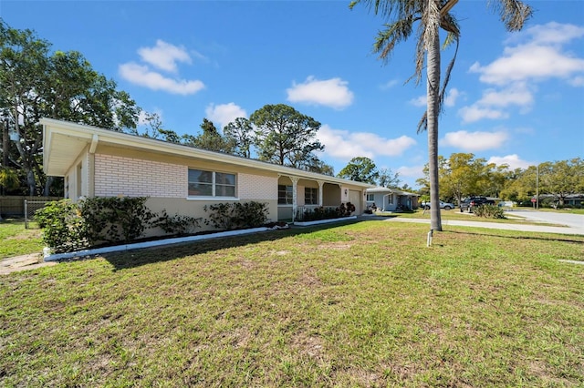 ranch-style house featuring a front lawn, fence, and brick siding