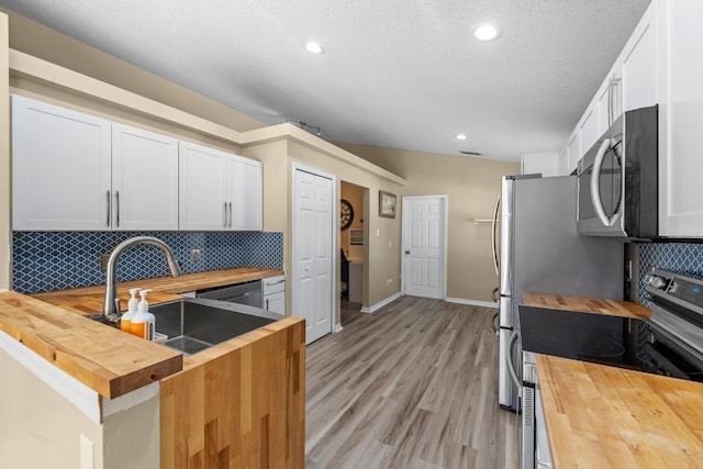 kitchen featuring backsplash, appliances with stainless steel finishes, wood counters, and a sink