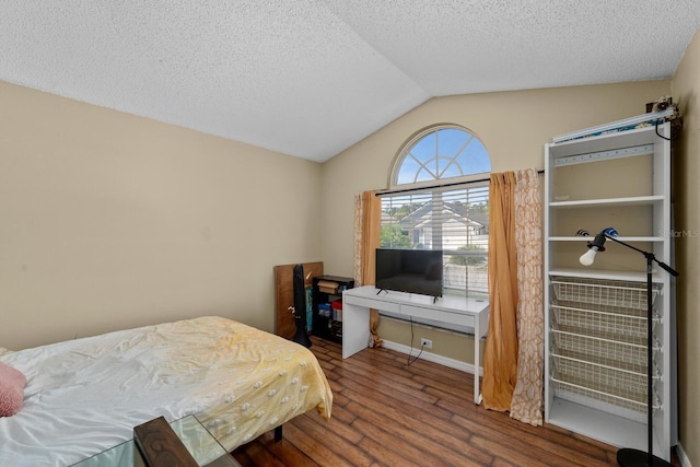 bedroom with a textured ceiling, lofted ceiling, and wood finished floors