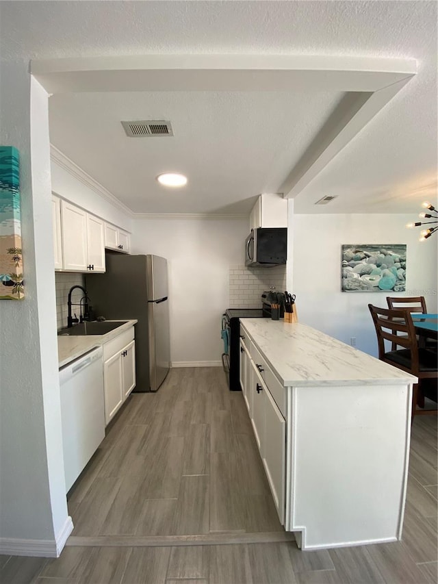 kitchen with white cabinetry, tasteful backsplash, visible vents, and appliances with stainless steel finishes