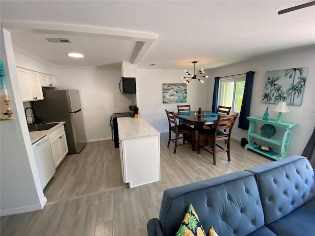 kitchen with white dishwasher, a sink, light countertops, white cabinets, and black electric range oven