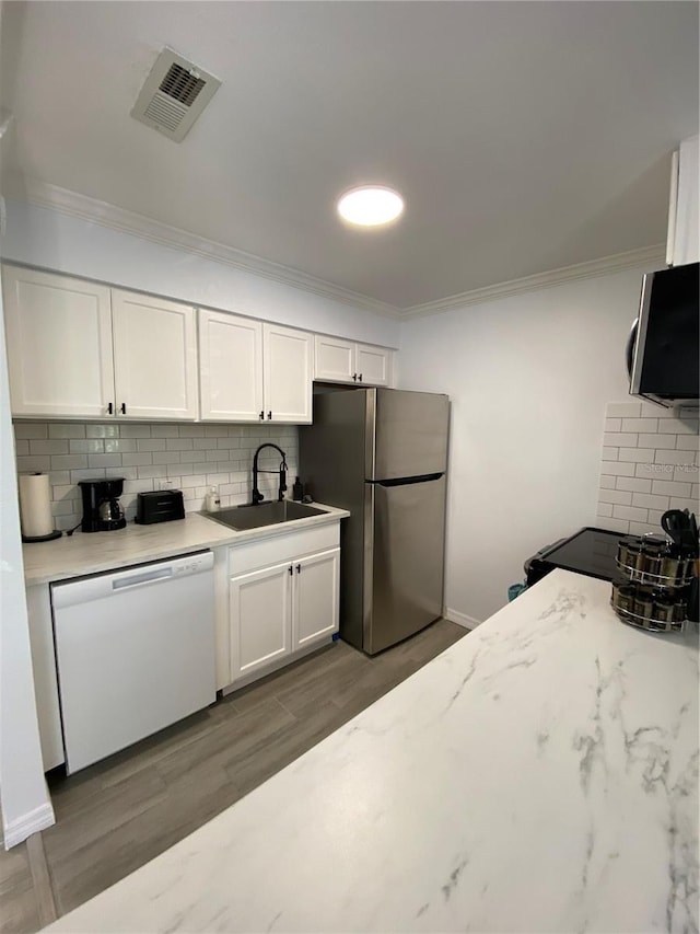 kitchen featuring visible vents, a sink, ornamental molding, stainless steel appliances, and white cabinetry