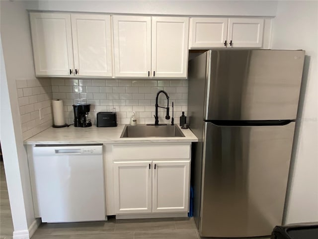 kitchen with white cabinets, dishwasher, freestanding refrigerator, and a sink