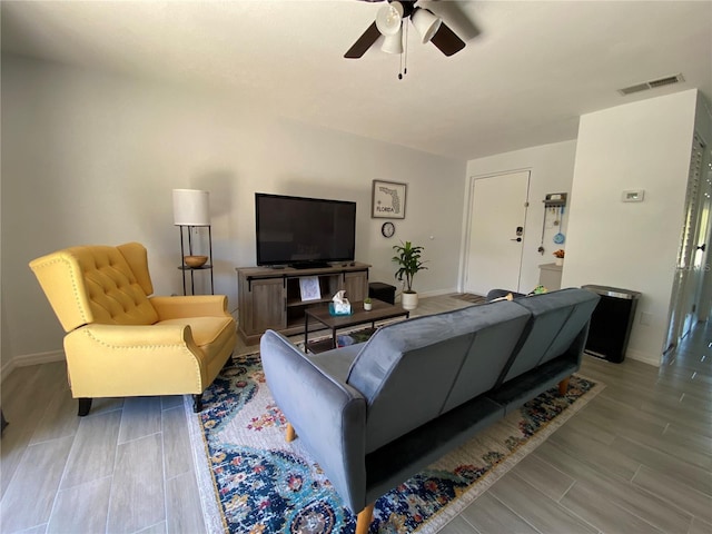 living room featuring wood finish floors, baseboards, visible vents, and ceiling fan